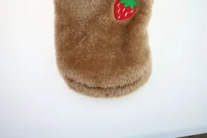 Close-up detail of brown plush pet clothes featuring a cute strawberry embroidery patch.