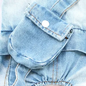 Close-up detail of light blue washed denim dog jumpsuit featuring a functional pocket.