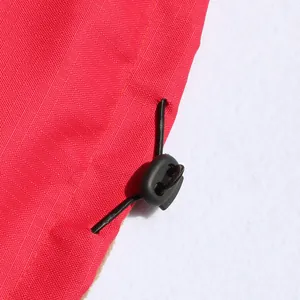 Primer plano de chaqueta roja para perro con tela ripstop impermeable y cordón ajustable.