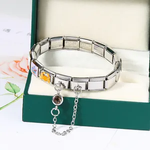 Close-up of a silver stainless steel Italian modular bracelet with a crab charm and safety chain