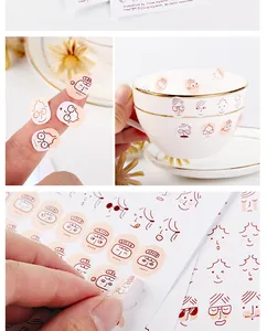 Detail shot of transparent cute face stickers used on a teacup and fingers