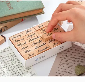 Detailed view of vintage wooden month stamps being picked from a white storage box.