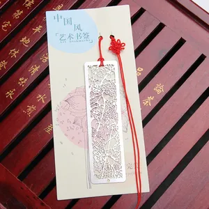 Hollow-out metal bookmark with red tassel in traditional Chinese lotus design.