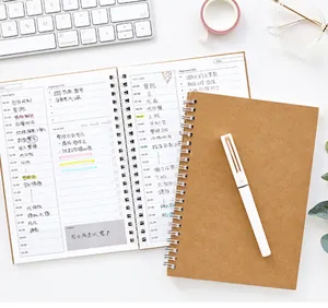 Close-up of an A5 kraft spiral daily planner with a white pen on an organized desk.