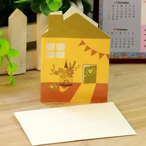 Creative house-shaped hollow greeting card with a white envelope on a wooden desk