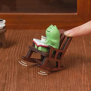 Cute miniature green frog figurine on a wooden rocking chair for desktop or car decor