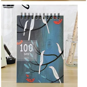 Planificateur de 100 jours artistique avec illustration d'oiseau et reliure spirale.