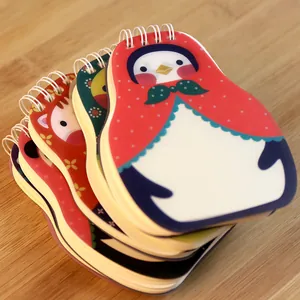 Stack of creative animal shaped notebooks with headscarf design on wooden table
