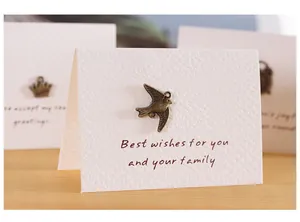 Primo piano di un biglietto d'auguri vintage con ciondolo uccello in bronzo e dedica.