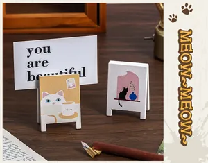 Detail shot of cartoon cat wooden memo clips used as a desktop photo holder.