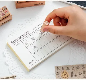Close-up of a wooden stamp being used on a habit tracker notepad for DIY journaling.