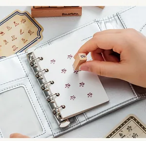 Detailed view of using a small wooden stamp on a notebook inside a silver binder