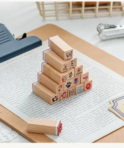 Close-up view of 12 stacked beech wood stamps with various DIY decorative patterns