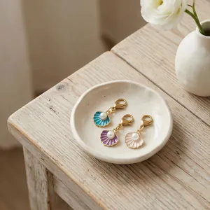 Detail van schelp- en parelhangers in blauw, paars en roze met gouden sluitingen.