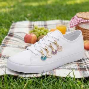 Detailweergave van kleurrijke schelp schoenbedeltjes met parels op witte sneakers
