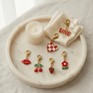 Close-up van diverse rood geëmailleerde bedeltjes met kreeftsluitingen voor DIY-sieraden.