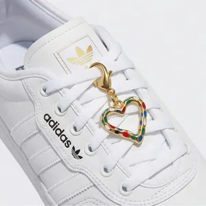 Detail van een gouden hartbedeltje met kleurrijke stippen als accessoire voor schoenen.