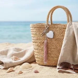 Detail van hartvormige spiegel en lippenstifthouder-sleutelhanger op een rieten strandtas
