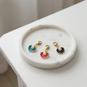 Detail van schelpvormige parelbedels met gouden kreeftsluitingen in blauw, rood en zwart.