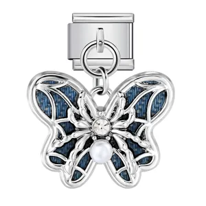 Nahaufnahme eines silbernen Schmetterlings-Charms mit blauen Denim-Flügeln und Perle.