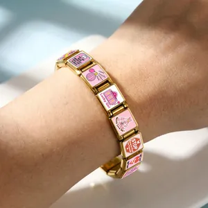 Gros plan d'un bracelet italien en acier doré avec des breloques roses motivantes.