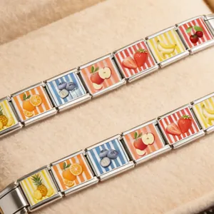 Detailed macro view of stainless steel Italian charm bracelets with colorful fruit patterns.