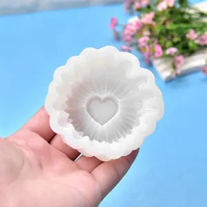 Nahaufnahme einer weißen Silikonform in Gänseblümchenform mit Herzmitte in der Hand
