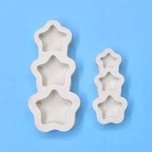 Bovenaanzicht van twee witte 3-gaats ster siliconen mallen voor DIY kaarsen maken op blauw.