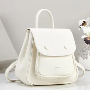 Close-up detail of white pebbled leather backpack showing flap and textured finish