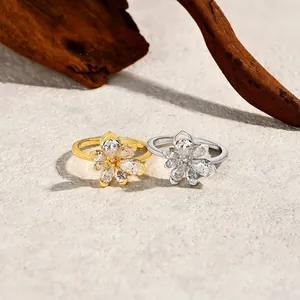 Detailed shot of two flower-shaped rings with sparkling zircons in gold and silver