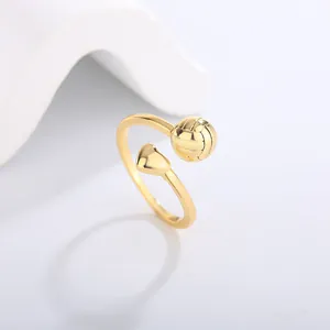 Macro view of gold sports ring featuring volleyball and heart design on white background