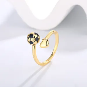Close-up detail of a minimalist adjustable golden ring with soccer ball and heart charms