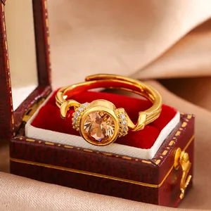 Close-up of gold-plated ring with oval champagne gemstone and sparkling pavé diamonds
