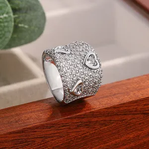 Nahaufnahme eines luxuriösen breiten Rings mit Pavé-Moissanit-Steinen und Herzmotiven.