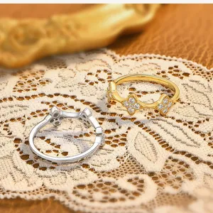 Elegant gold and silver clover-patterned rings set on a delicate white lace background.