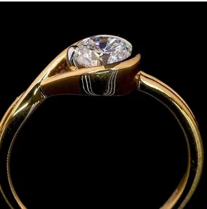 Close-up of minimalist gold plated moissanite ring with geometric wrap design.