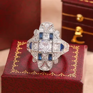 Dettaglio di un anello reale vintage con pietre blu e bianche su scatola rossa