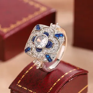 Close-up of vintage square zirconia ring with blue and white stones on a red gift box.