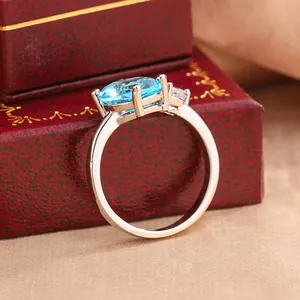 Side view of elegant ring with oval blue gemstone and white cubic zirconia accents