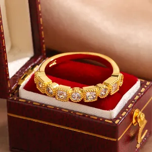 Close-up of vintage gold-plated lace ring with round and square cubic zirconia stones.