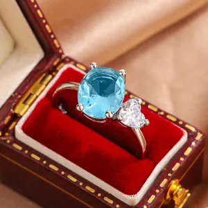 Detail view of oval blue gemstone and heart zircon ring in red velvet box