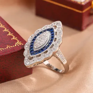 Gros plan d'une bague en argent de style vintage avec saphir bleu et cristaux blancs.