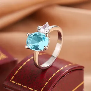 Detail shot of a silver band ring with an oval blue gemstone and heart-shaped CZ
