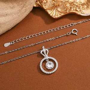 Close-up detail of an elegant silver necklace featuring a crown and circular zircon pendant