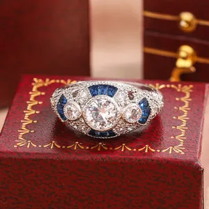 Detailed macro view of an ornate vintage ring with blue sapphire accents on a red gift box.