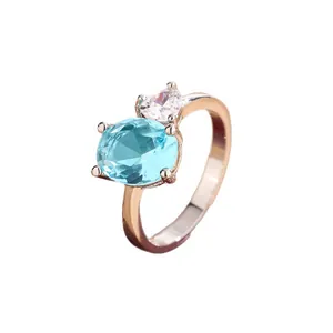 Rose gold ring featuring an oval blue gemstone and a heart-shaped white zircon.