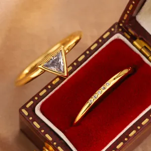 Macro detail of elegant gold-plated rings featuring a triangle zircon stone and micro-pave crystals