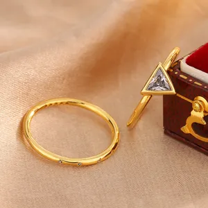 Macro detail view of two minimalist gold-plated rings featuring clear zircon settings