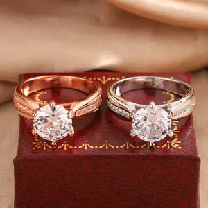 Detailed close-up showing rose gold and silver moissanite rings set on a vintage red gift box
