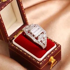 Close-up view of a luxury emerald-cut zircon ring inside a red velvet jewelry box on gold satin